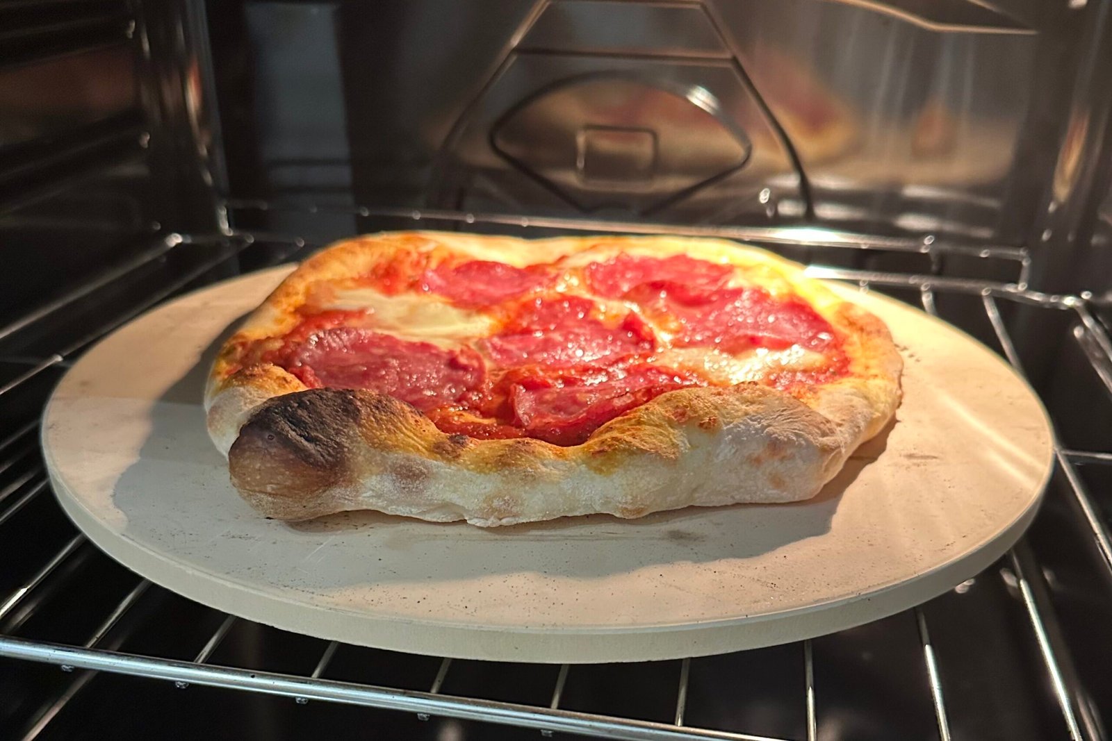 Pizzakivi sähköllä toimivassa kotiuunissa, jonka päällä pizza paistumassa.